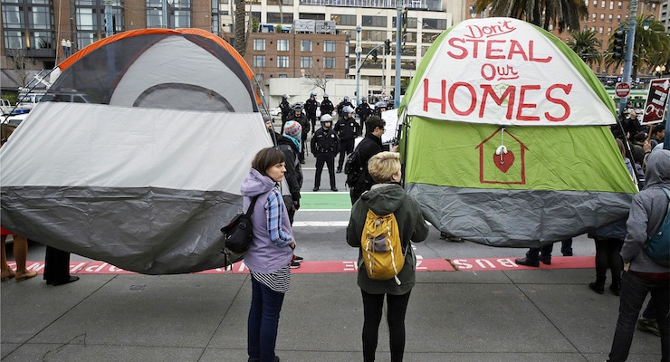 Demonstrators hold up tents during a protest to demand city officials do more to help homeless people outside Super Bowl City, a pro-football's weeklong theme park near the famed Ferry Building in San Francisco on Wednesday, Feb. 3, 2016. Dozens protested what they say is San Francisco Mayor Ed Lee's plan to push homeless people out of the scenic bay-front Embarcadero, where Super Bowl festivities are being held. (AP Photo/Eric Risberg)