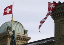 Workers hang up a Swiss flag on the Swiss parliament building in Bern, Switzerland, November 24, 2015. REUTERS/RUBEN SPRICH