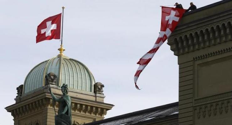 Workers hang up a Swiss flag on the Swiss parliament building in Bern, Switzerland, November 24, 2015. REUTERS/RUBEN SPRICH