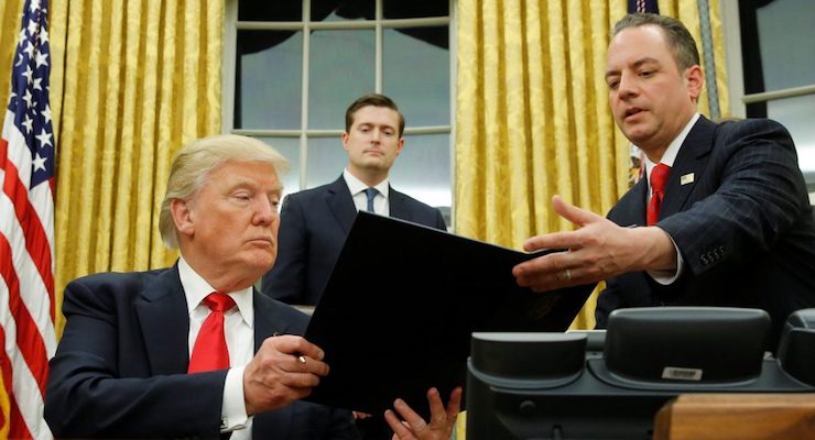 President Donald J. Trump, left, hands Chief of Staff Reince Priebus, right, an executive order in the Oval Office in Washington, Friday. (Photo: Reuters)