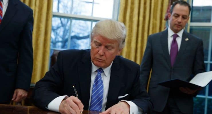 President Donald Trump signs an executive order to withdraw the U.S. from the 12-nation Trans-Pacific Partnership trade pact agreed to under the Obama administration, Monday, Jan. 23, 2017, in the Oval Office of the White House in Washington. (AP Photo/Evan Vucci)