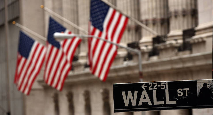 American flags hang outside the New York Stock Exchange (NYSE) behind the street sign on Wall Street in New York City.