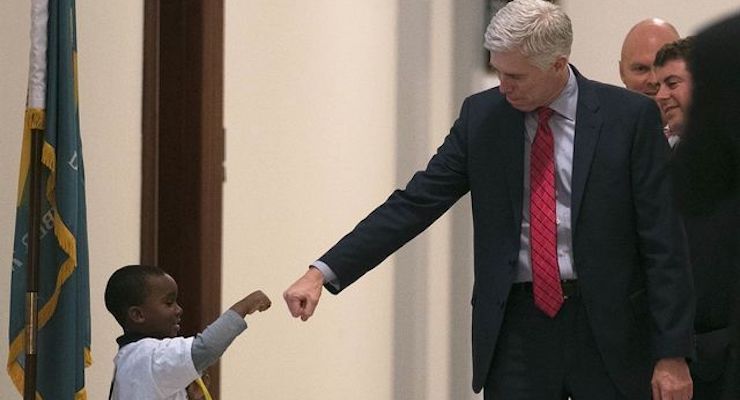 Judge Neil Gorsuch, who served on the 10th Circuit before being nominated to the U.S. Supreme Court by President Donald J. Trump, stops to give a young boy a fist bump before heading into the Senate confirmation hearing on Capitol Hill.