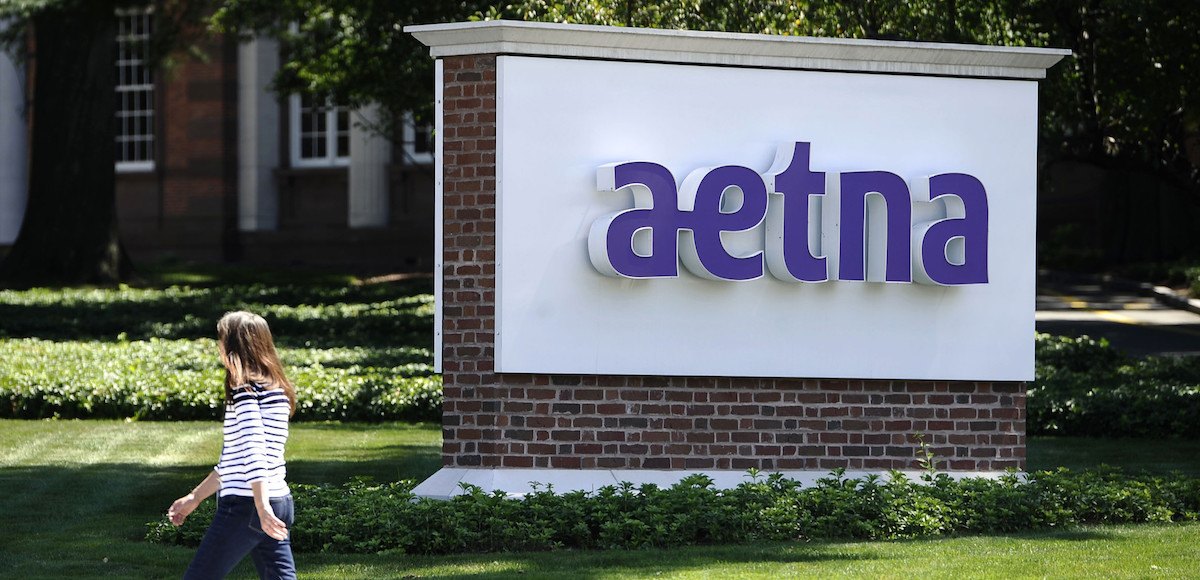 In this Tuesday, Aug. 19, 2014 file photo, pedestrian walks past a sign for health insurer Aetna Inc., at the company headquarters in Hartford. (Photo: AP)