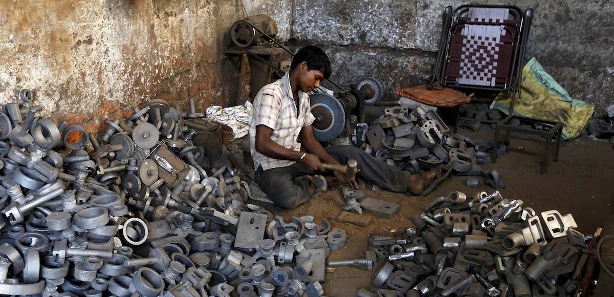 A worker separates casting joints of gearboxes inside a small-scale automobile manufacturing unit in Ahmedabad, India, October 12, 2015. (Photo: Reuters)