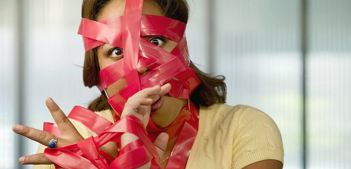 Businesswoman wrapped in red tape. (Occupational Licensing Graphic)