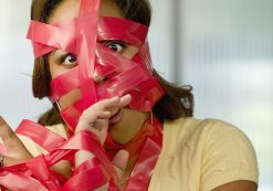 Businesswoman wrapped in red tape. (Occupational Licensing Graphic)