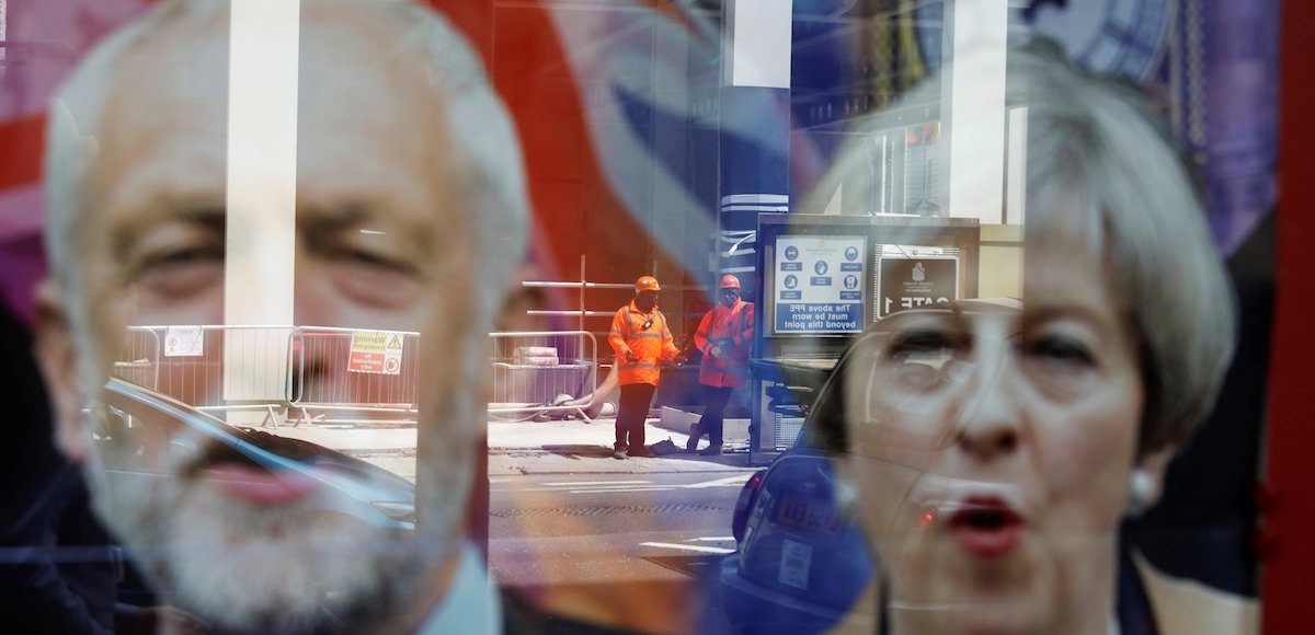 Workers in protective equipment are reflected in the window of a betting shop with a display inviting customers to place bets on tbe result of the general election with images of Britain's Prime Minister Theresa May and opposition Labour Party leader Jeremy Corbyn, in London, June 7, 2017. (Photo: Reuters)