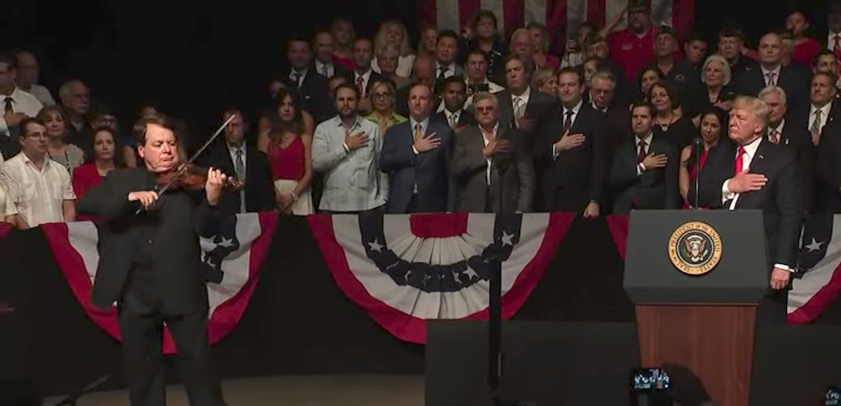 President Donald J. Trump places his hand over his heart as Luis, a Cuban-American dissident, plays the Star Bangled Banner during the President's announcement of his new policy on Cuba in Miami, Florida on June 16, 2017. (Photo: People's Pundit Daily)