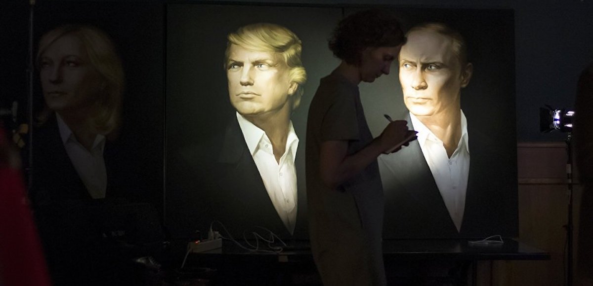 A journalist writes a material as she watches a live telecast of the U.S. presidential election standing at portraits of U.S. presidential candidate Donald Trump and Russian President Vladimir Putin in the Union Jack pub in Moscow, Russia, Wednesday, Nov. 9, 2016. Russia's lower house of parliament is applauding the election of Trump as U.S. president. (Photo: AP)