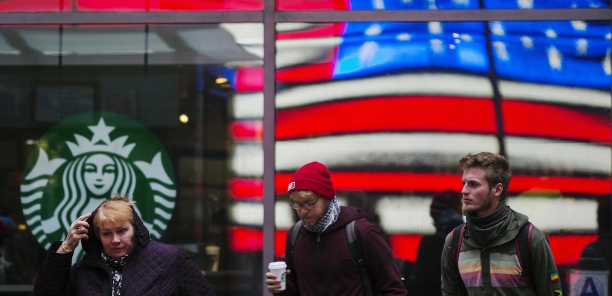 A woman pulls a hood over her head as she walks out of a Starbucks store into the cold wind at Times Square in New York, March 25, 2013. (Photo: Reuters)