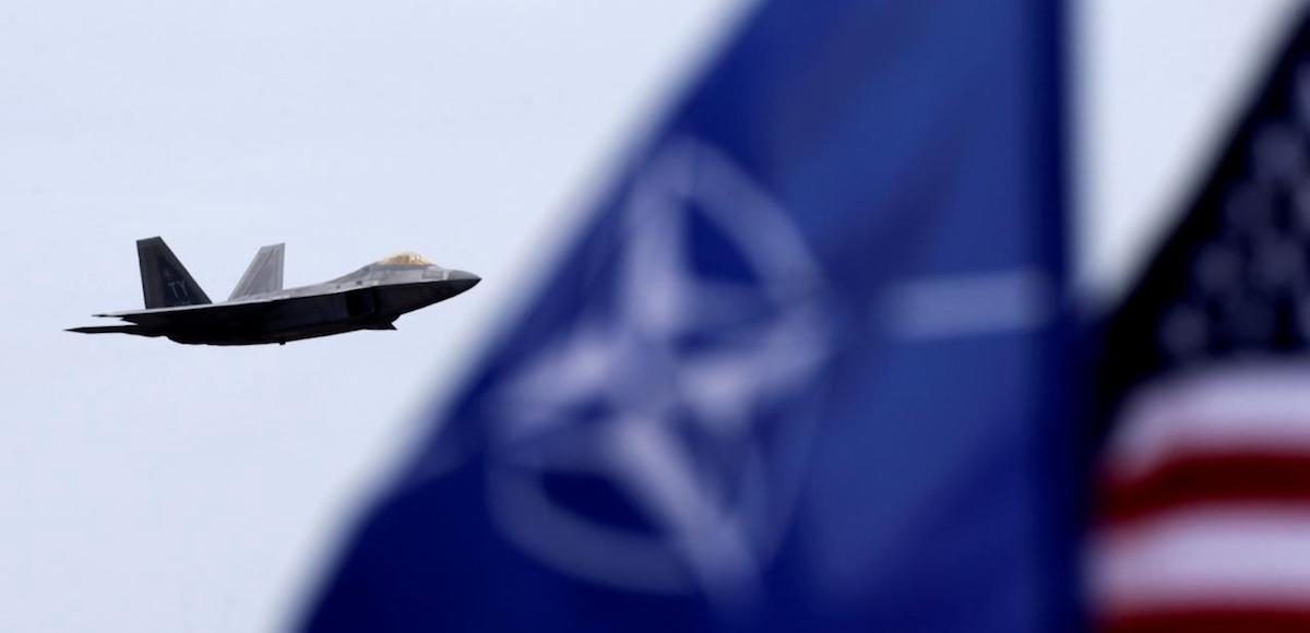 U.S. and North Atlantic Treaty Organization (NATO) flags flutter as U.S. Air Force F-22 Raptor fighter flies over the military air base in Siauliai, Lithuania, April 27, 2016. (Photo: Reuters)