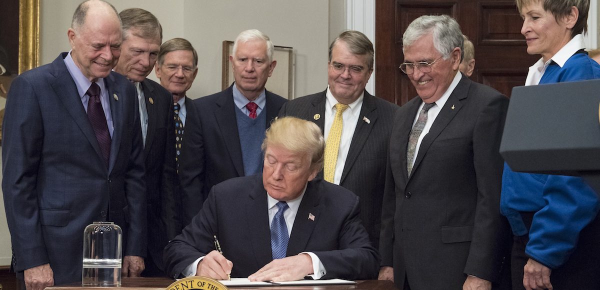 President Donald Trump signs the Presidential Space Directive - 1, directing NASA to return to the moon, alongside members of the Senate, Congress, NASA, and commercial space companies in the Roosevelt room of the White House in Washington, Monday, Dec. 11, 2017. Photo Credit: (NASA/Aubrey Gemignani)