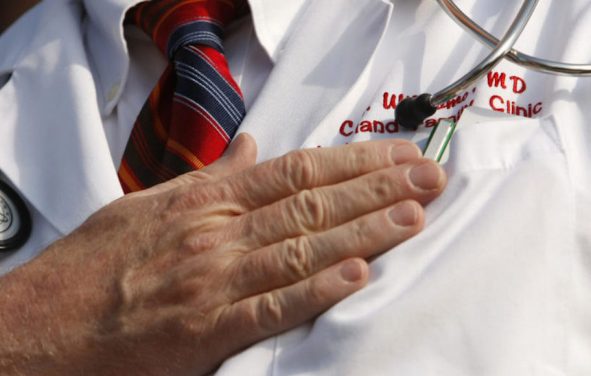 A doctor puts his hand over his chest during a 