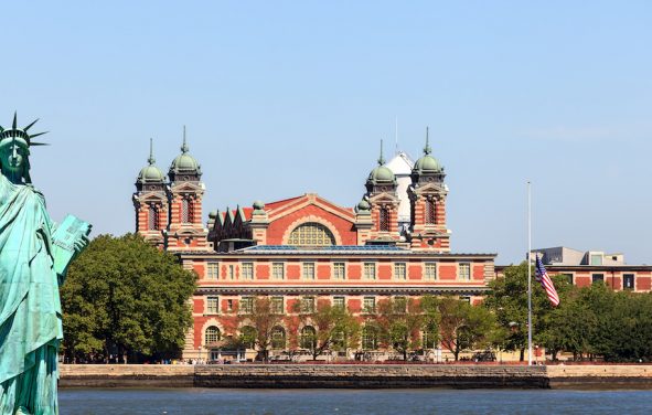 The Statue of Liberty in front of Ellis Island across from New York City. (Photo: AdobeStock/UbjsP)