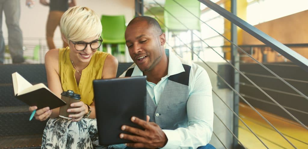 A team of millennial business owners collaborating on an online project using a touchpad tablet in a modern office space. (Photo: AdobeStock/AYAimages)