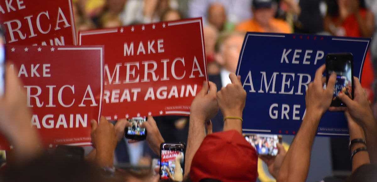 Supporters of President Donald Trump hold up Make America Great American and Keep America Great signs A supporter of Donald Trump dons a T-shirt with a new twist on an old joke targeting Hillary Clinton during a rally in Tampa, Florida on Tuesday, July 31, 2018. (Photo: Laura Baris/People's Pundit Daily)