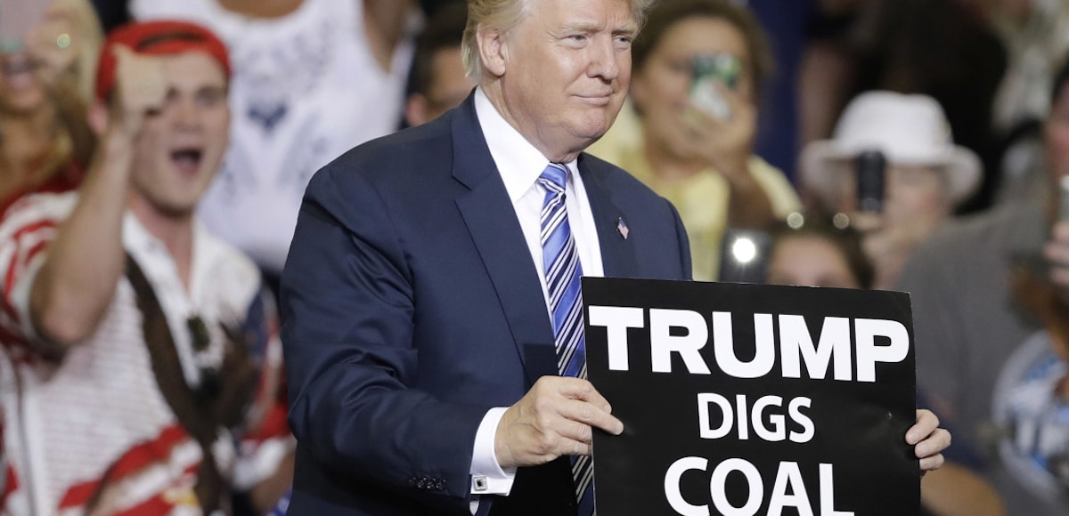 Donald Trump holds up a "Trump Digs Coal" placard at a rally promising to bring back the coal industry in West Virginia, Ohio and elsewhere.
