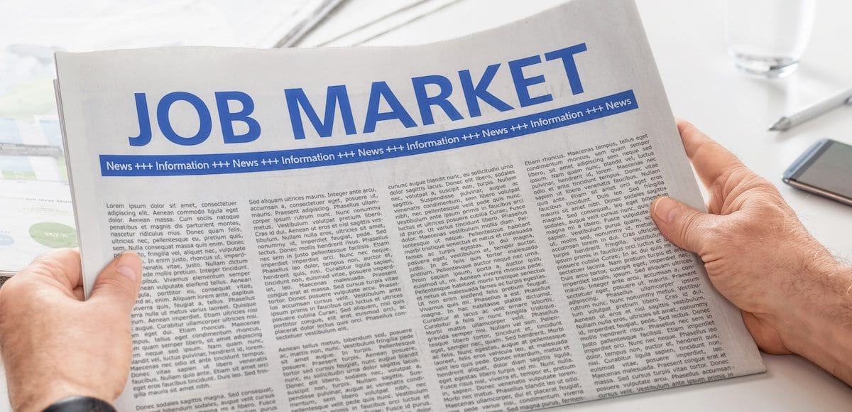 Man reading newspaper with the headline Job Market. (Photo: AdobeStock)