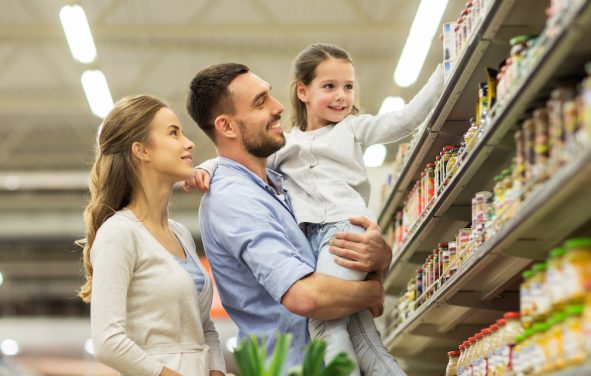 Sale, consumerism and people concept - happy family with child and shopping cart buying food at grocery store or supermarket. (Photo: PPD/AdobeStock/Syda Productions)