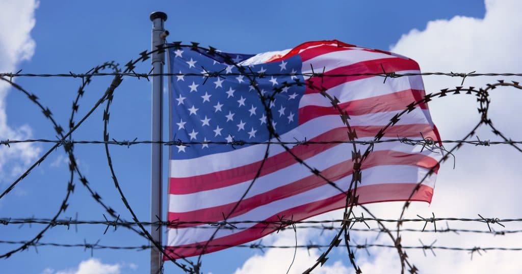 An American flag flying behind barbed wire at the U.S. southern border with Mexico. (Photo: AdobeStock)