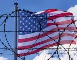 An American flag flying behind barbed wire at the U.S. southern border with Mexico. (Photo: AdobeStock)