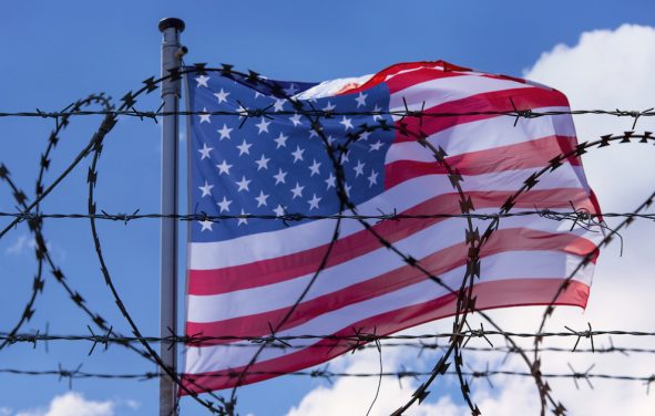 An American flag flying behind barbed wire at the U.S. southern border with Mexico. (Photo: AdobeStock)