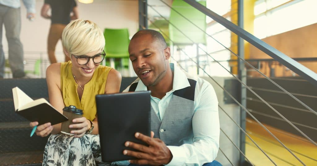 A team of millennial business owners collaborating on an online project using a touchpad tablet in a modern office space. (Photo: AdobeStock/AYAimages)