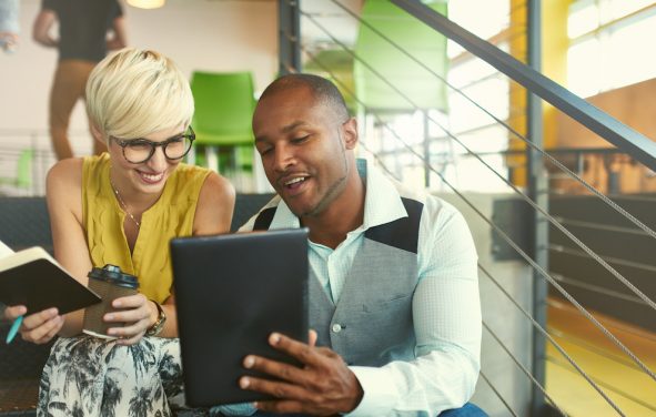 A team of millennial business owners collaborating on an online project using a touchpad tablet in a modern office space. (Photo: AdobeStock/AYAimages)