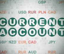 Current account balance concept: painted green text Current Account on digital data paper background with currency. (Photo: AdobeStock)