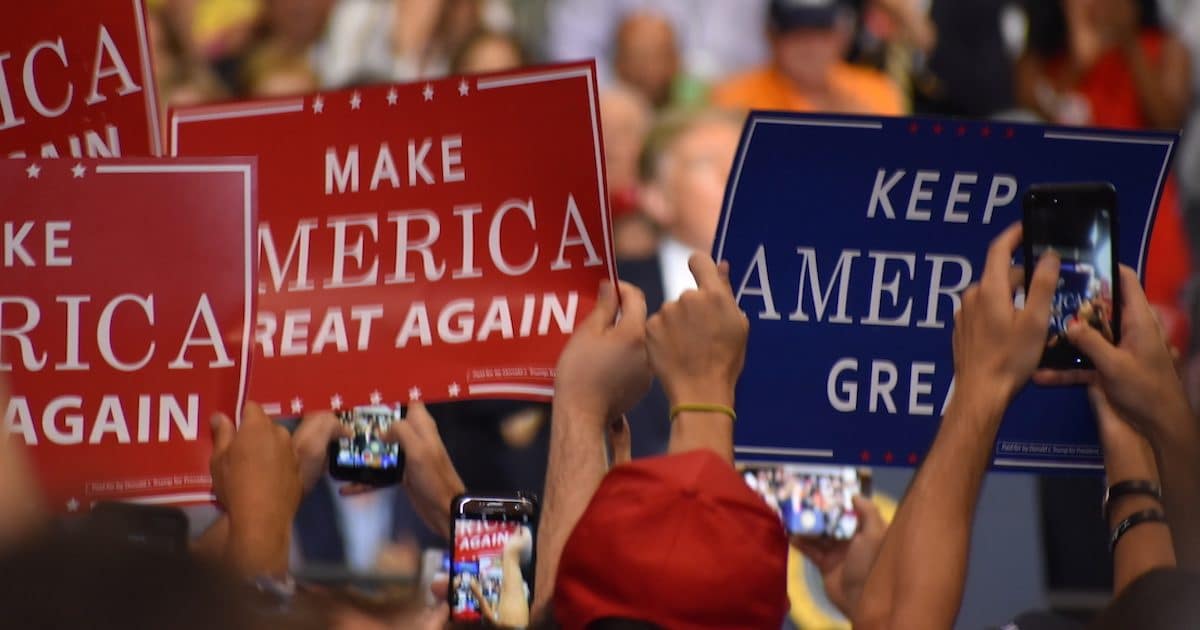 Supporters of President Donald Trump hold up Make America Great American and Keep America Great signs A supporter of Donald Trump dons a T-shirt with a new twist on an old joke targeting Hillary Clinton during a rally in Tampa, Florida on Tuesday, July 31, 2018. (Photo: Laura Baris/People's Pundit Daily)