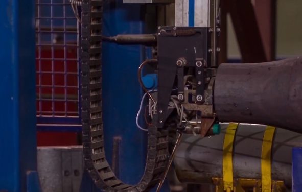 Manufacture of rails for trains and freight wagon, boxcars. Rail manufacturing plant. Stack of steel round bar - iron metal rail lines material for industry construction in warehouse. (Photo: AdobeStock)
