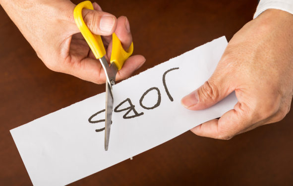 Closeup view of a business man cutting a piece of paper with the word jobs written on it, concept for job cut reports. (Photo: AdobeStock)
