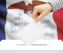 Voting, elections and state polls concept: Ballot box with state flag in the background - Iowa. (Photo: AdobeStock)