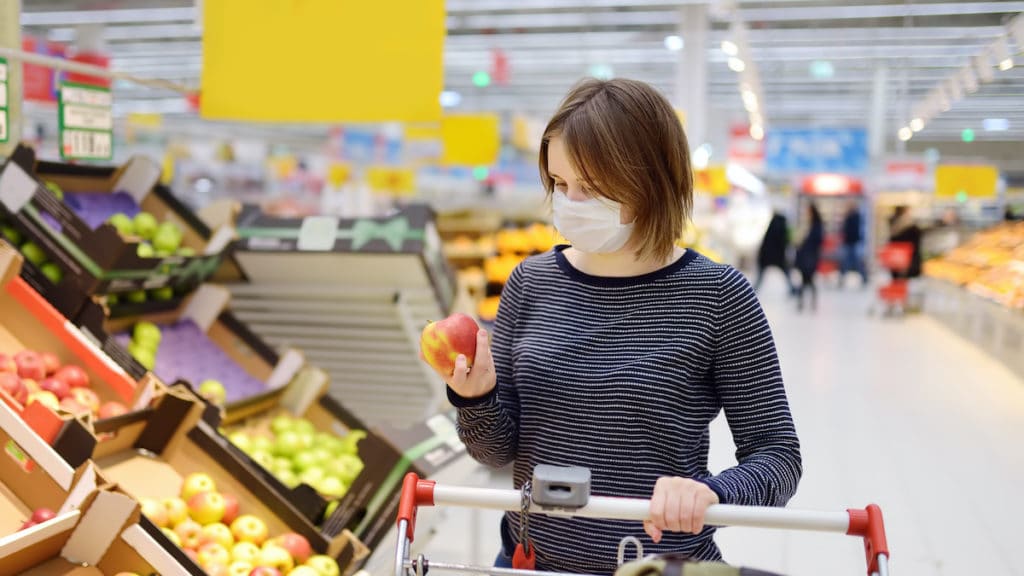 A young woman consumer wearing a disposable medical mask while shopping at the supermarket during the Chinese Coronavirus (COVID-19) outbreak. (Photo: AdobeStock)