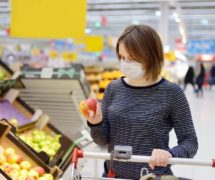 A young woman consumer wearing a disposable medical mask while shopping at the supermarket during the Chinese Coronavirus (COVID-19) outbreak. (Photo: AdobeStock)