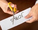 Closeup view of a business man cutting a piece of paper with the word jobs written on it, concept for job cut reports. (Photo: AdobeStock)