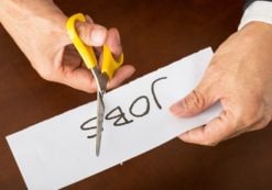Closeup view of a business man cutting a piece of paper with the word jobs written on it, concept for job cut reports. (Photo: AdobeStock)