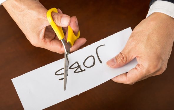 Closeup view of a business man cutting a piece of paper with the word jobs written on it, concept for job cut reports. (Photo: AdobeStock)