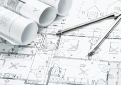 Construction planning drawings on the table and two yellow pencils to illustrate total construction spending data and projects. (Photo: AdobeStock)