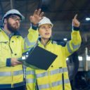 Two engineers — one male and one female — in a manufacturing factory discussing operations in industrial production. (Photo: AdobeStock)