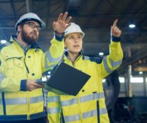 Two engineers — one male and one female — in a manufacturing factory discussing operations in industrial production. (Photo: AdobeStock)